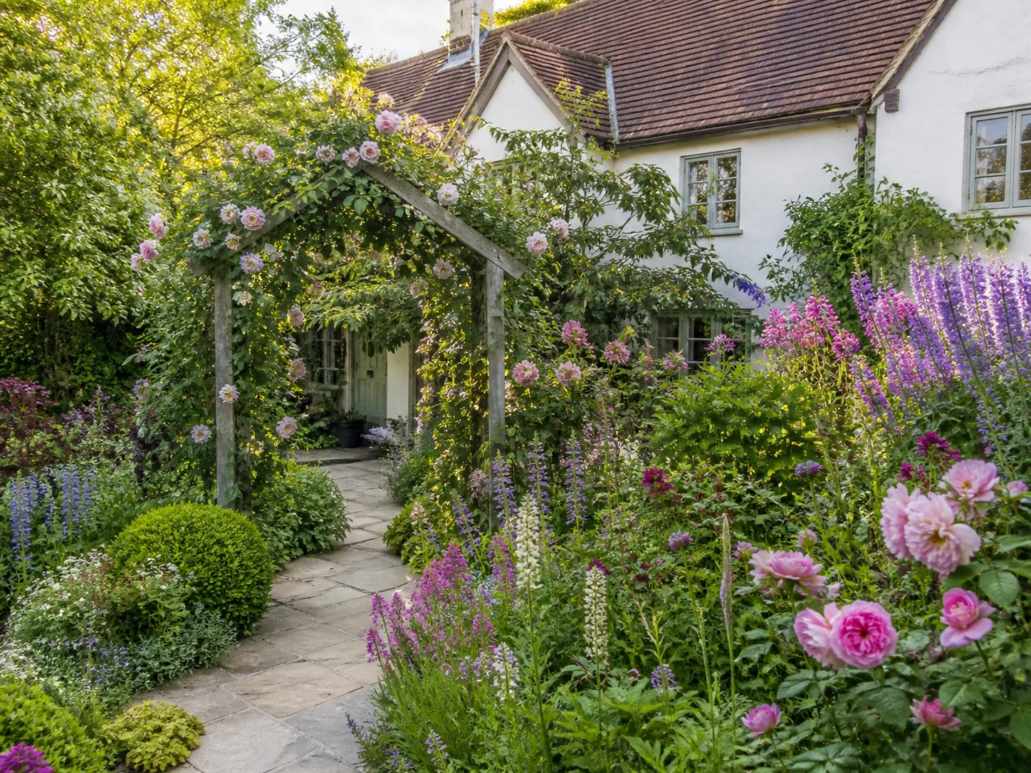 English cottage garden with layered blooms and a charming arbor