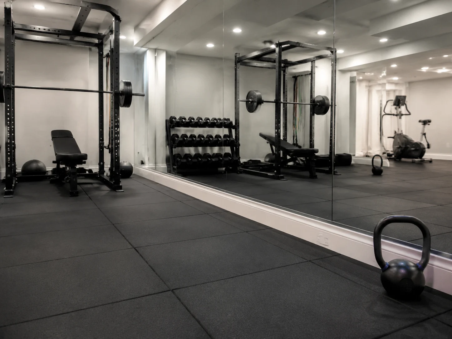 Gym detail with rubber flooring, wall mirrors, and bright overhead lighting