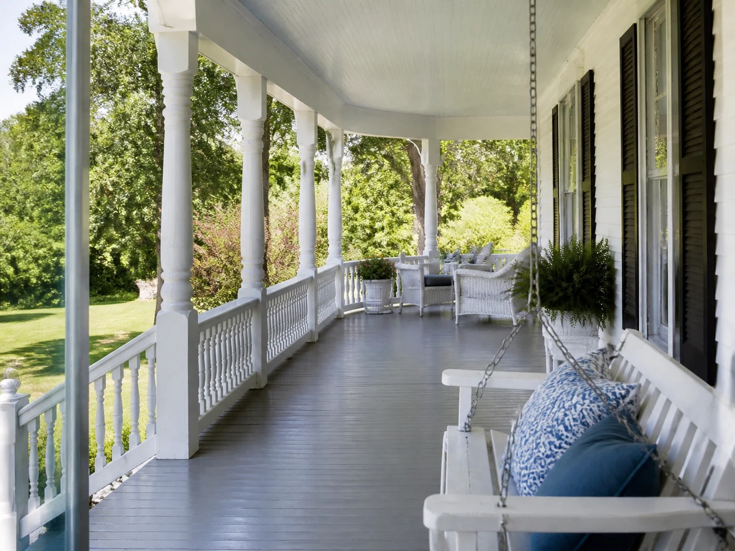 Farmhouse wraparound porch with wood columns and porch swing