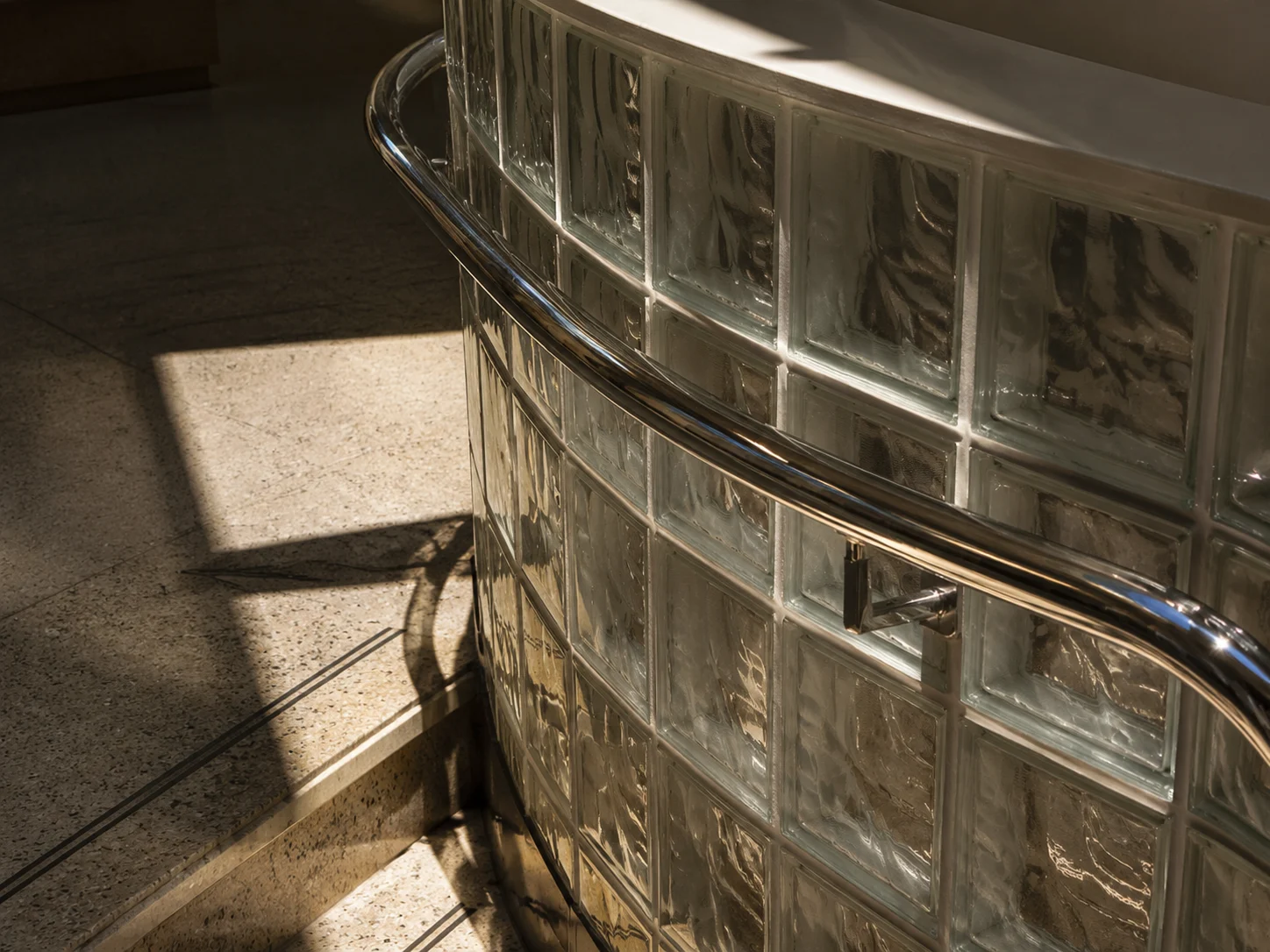 Curved glass block wall and chrome handrail