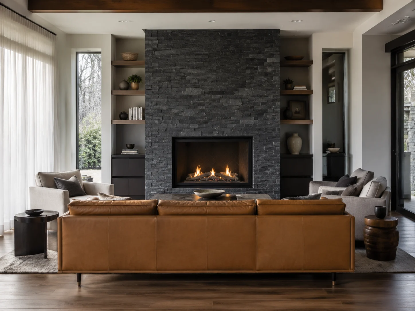 Living room seating arranged around a modern stone fireplace